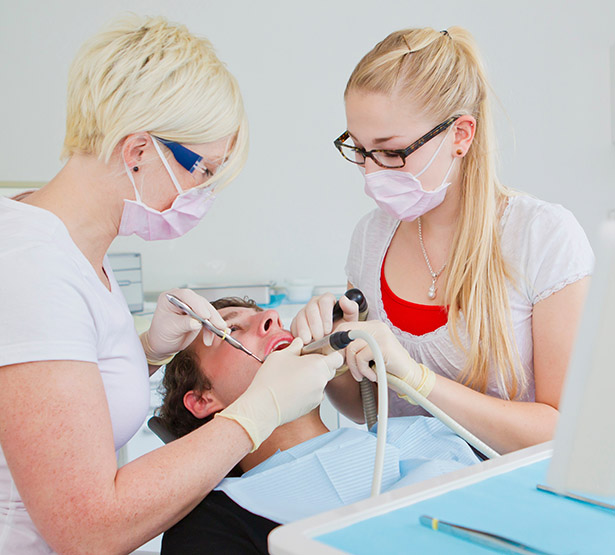 Un chirurgien-dentiste et son assistante dentaire pratiquent des soins sur un patient - MACSF