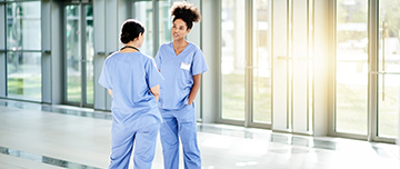 Deux femmes de la fonction publique hospitalière discutent dans un couloir de l'hôpital - MACSF