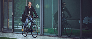 Un homme sur un vélo passe devant des baies vitrées - MACSF