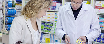 Un pharmacien renseigne une cliente sur la posologie d'un médicament