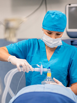 Une IADE applique un masque d'anesthésie sur un patient au bloc - MACSF
